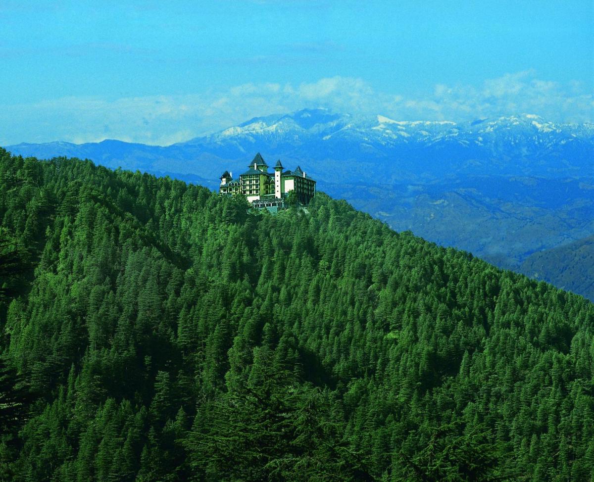 a house on top of a tree covered mountain at Wildflower Hall, An Oberoi Resort, Shimla in Shimla