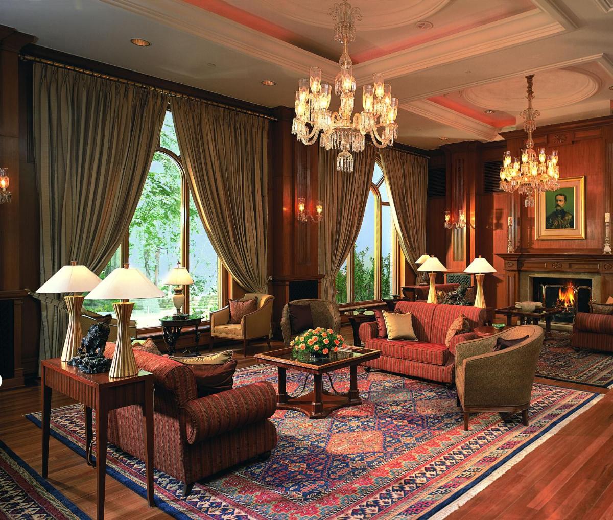 a living room with red furniture and a chandelier at Wildflower Hall, An Oberoi Resort, Shimla in Shimla