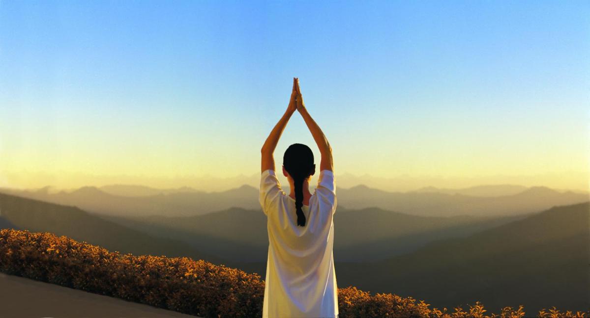a woman doing yoga on top of a mountain at Wildflower Hall, An Oberoi Resort, Shimla in Shimla