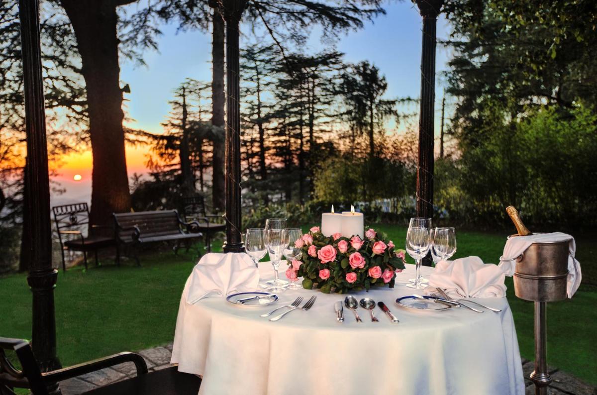 a table with a white table cloth and flowers on it at Wildflower Hall, An Oberoi Resort, Shimla in Shimla