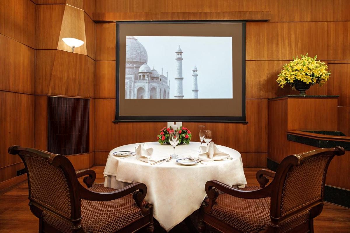 a table in a restaurant with a picture of a building at Wildflower Hall, An Oberoi Resort, Shimla in Shimla
