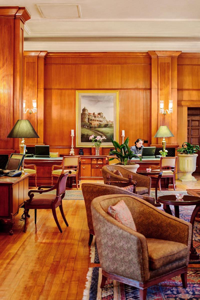 a room with chairs and tables and a person sitting at a desk at Wildflower Hall, An Oberoi Resort, Shimla in Shimla