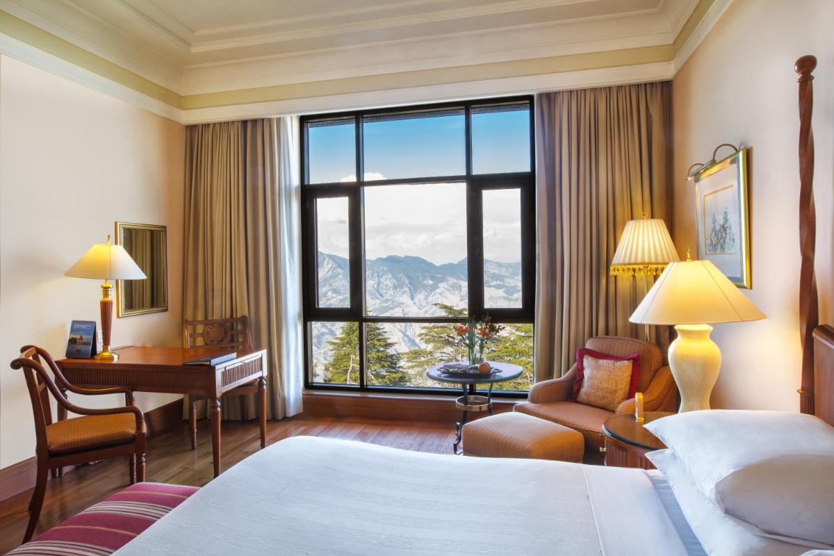 a hotel room with a bed and a desk and a window at Wildflower Hall, An Oberoi Resort, Shimla in Shimla