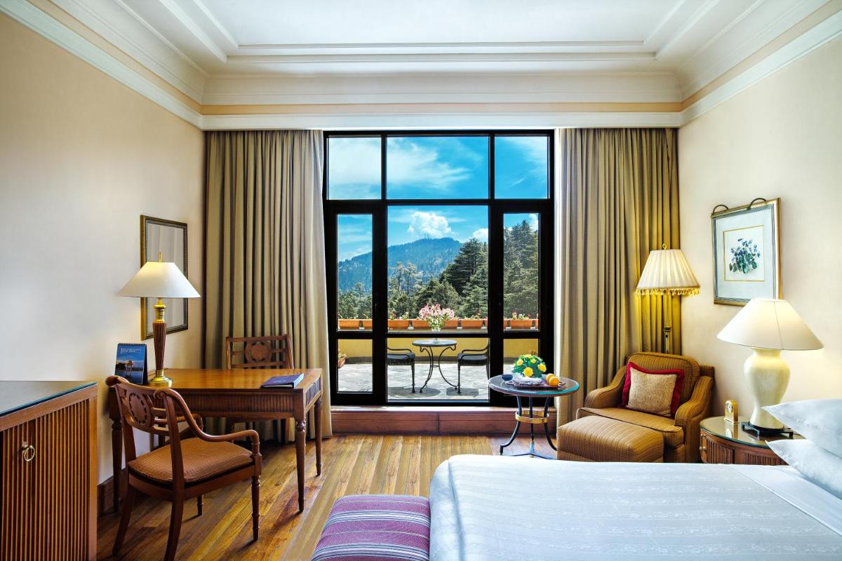 a hotel room with a bed and a desk and a room with a window at Wildflower Hall, An Oberoi Resort, Shimla in Shimla