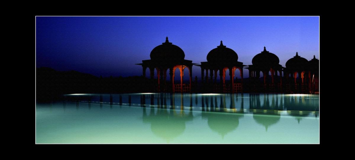 a mosque with its reflection in the water at night at Chunda Palace in Udaipur