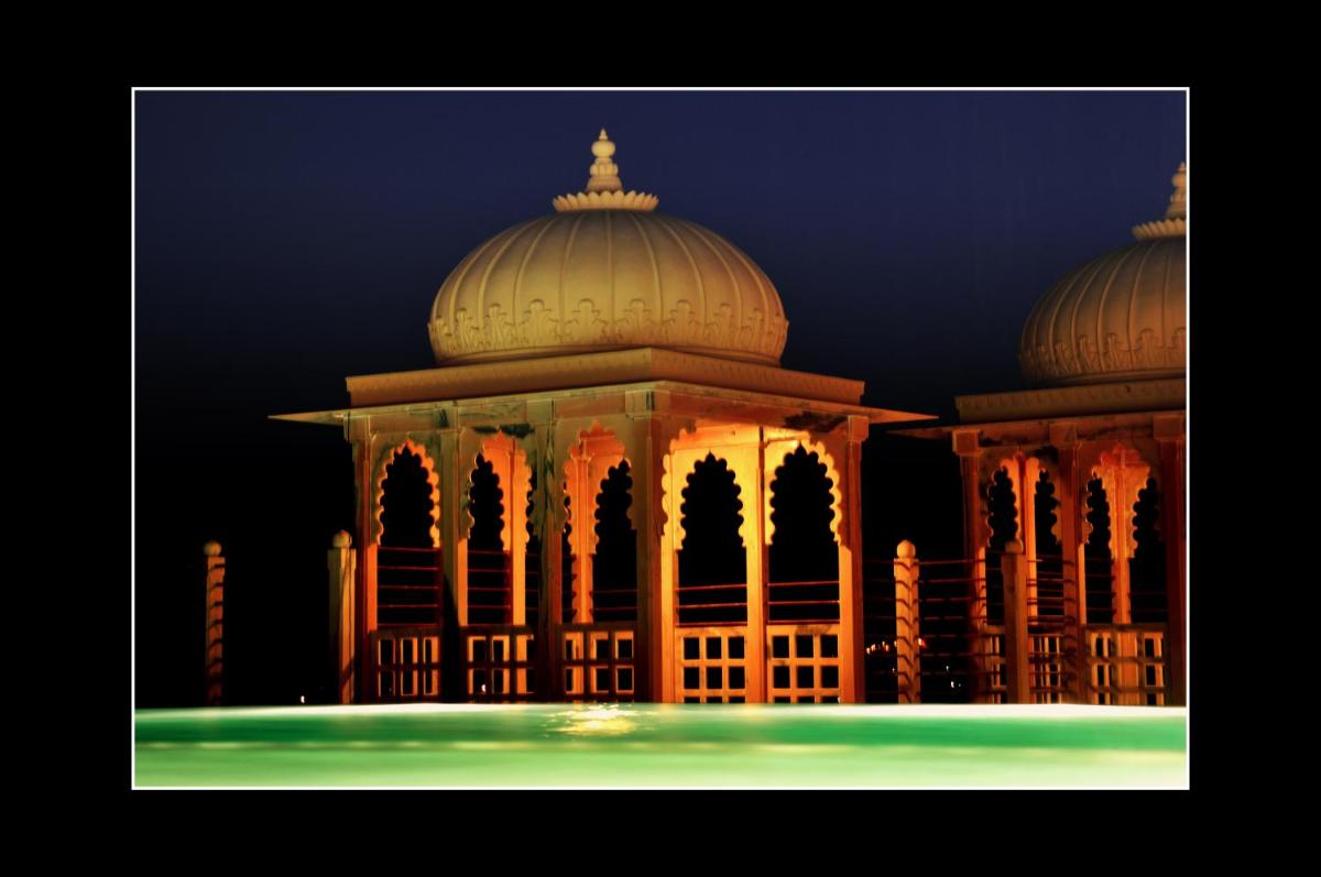 a lit up building with a fountain in front of it at Chunda Palace in Udaipur