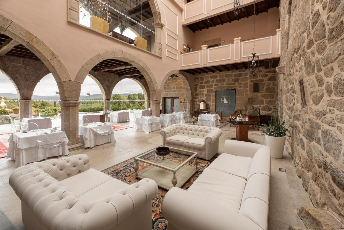 una sala de estar con muebles blancos y una pared de piedra. en Áurea Palacio de Sober by Eurostars Hotel Company, en Sober