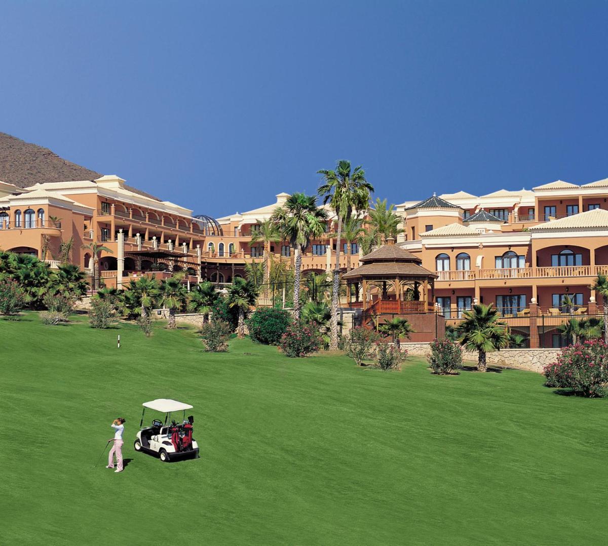Un carrito de golf en un campo frente a un edificio. en Hotel Las Madrigueras Golf Resort & Spa - Adults Only, en Playa de las Américas