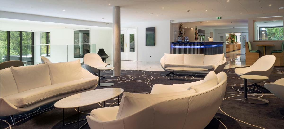 - un hall avec des canapés blancs, des tables et des chaises dans l'établissement 6717 Nature Hôtel & Spa Le Clos des Délices, à Ottrott