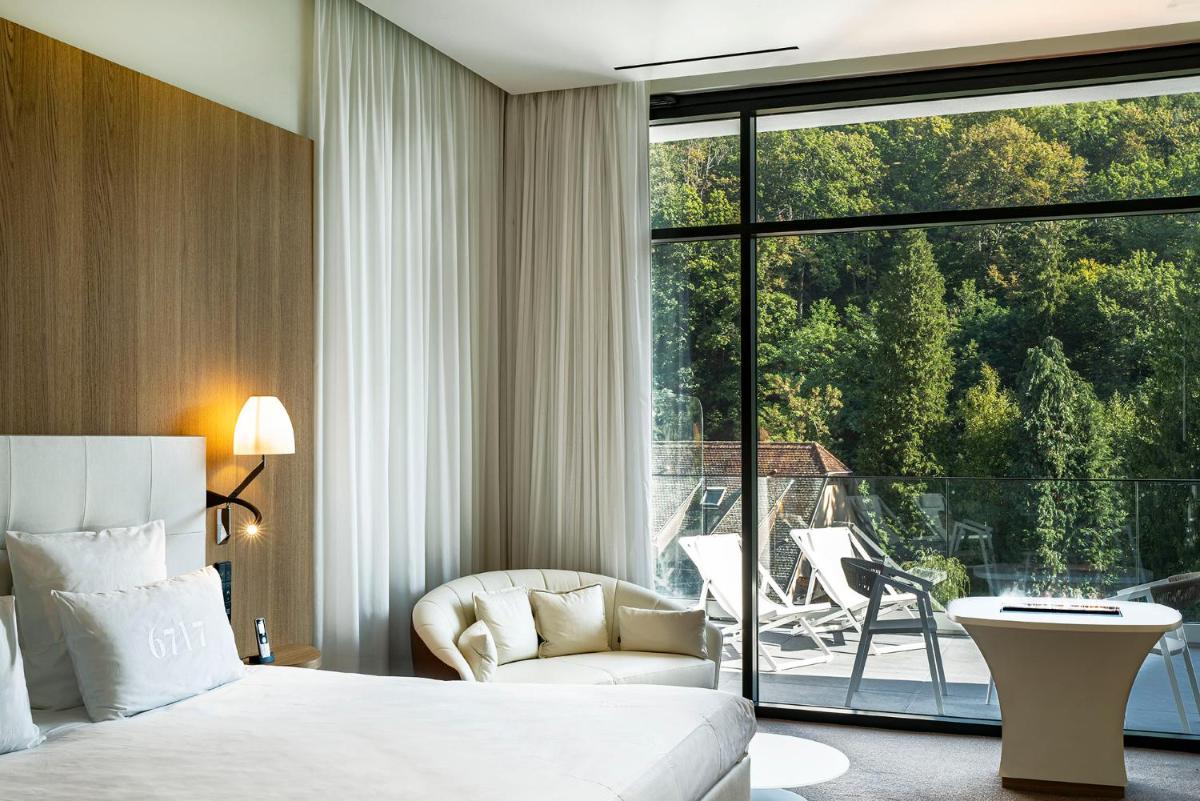 - une chambre avec un lit, une chaise et une grande fenêtre dans l'établissement 6717 Nature Hôtel & Spa Le Clos des Délices, à Ottrott