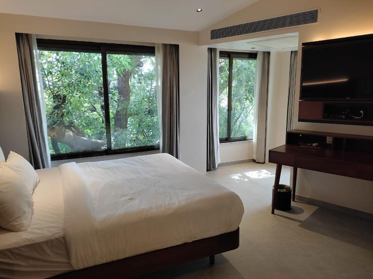 a bedroom with a bed and a large window at The Crown Goa in Panaji