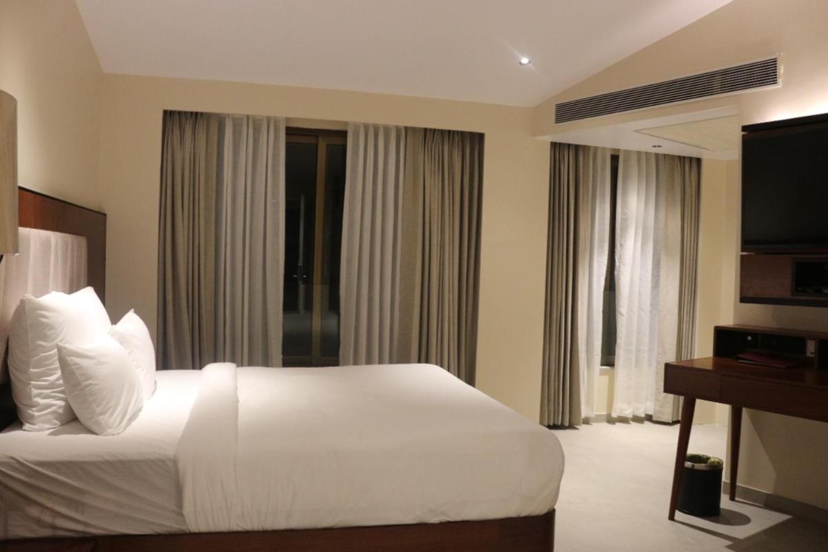 a hotel room with a white bed and a television at The Crown Goa in Panaji