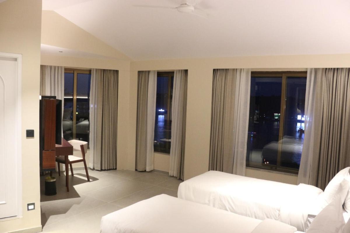 a hotel room with two beds and a balcony at The Crown Goa in Panaji