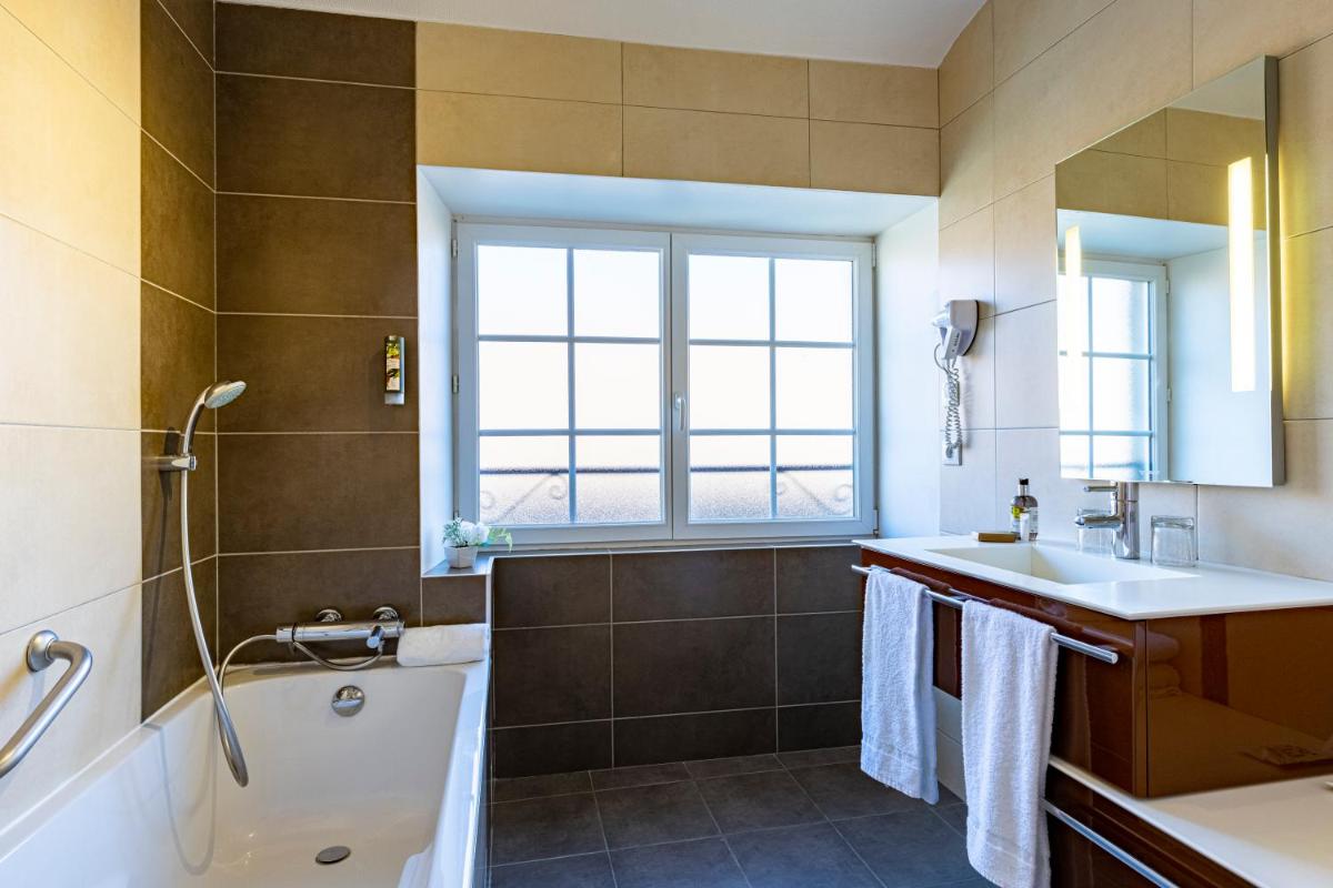 une salle de bain avec une baignoire et un lavabo et une baignoire tubermottermott dans l'établissement Logis Relais de la Source, à Saint-Seine-lʼAbbaye 32 autres photos