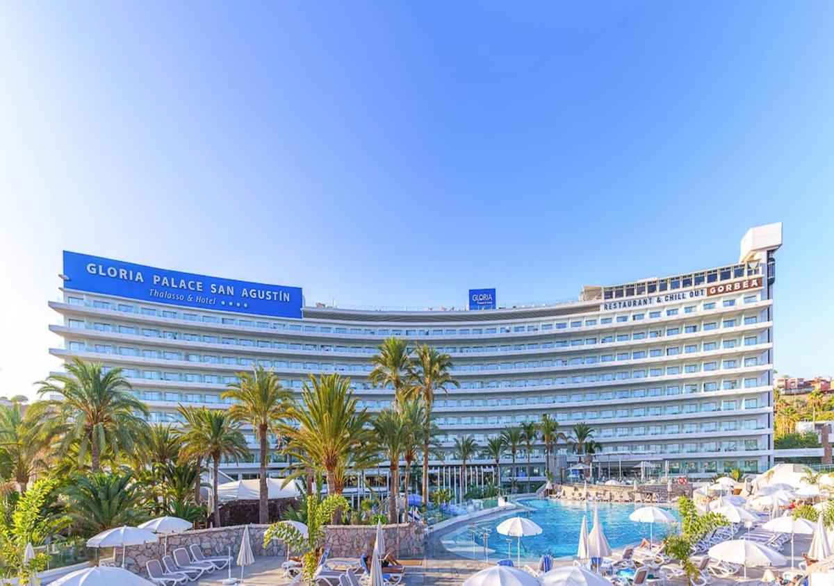 un gran hotel con piscina y palmeras en Gloria Palace San Agustín Thalasso & Hotel, en San Agustín