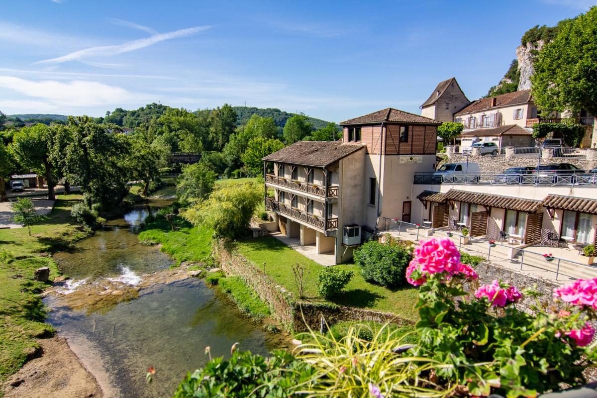 un bâtiment à côté d'une rivière fleurie dans l'établissement Hôtel Spa La Truite Dorée, à Vers