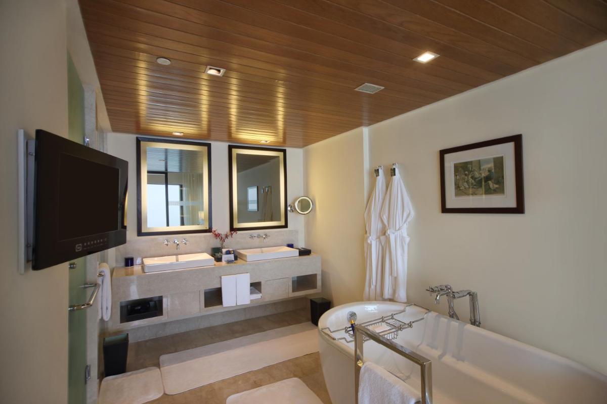 a bathroom with a tub and two sinks and a television at The Oberoi Mumbai in Mumbai