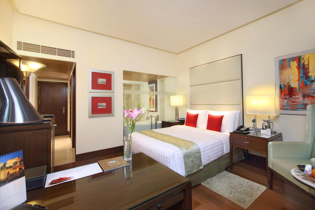 a hotel room with a bed and a desk with flowers at The Oberoi Mumbai in Mumbai