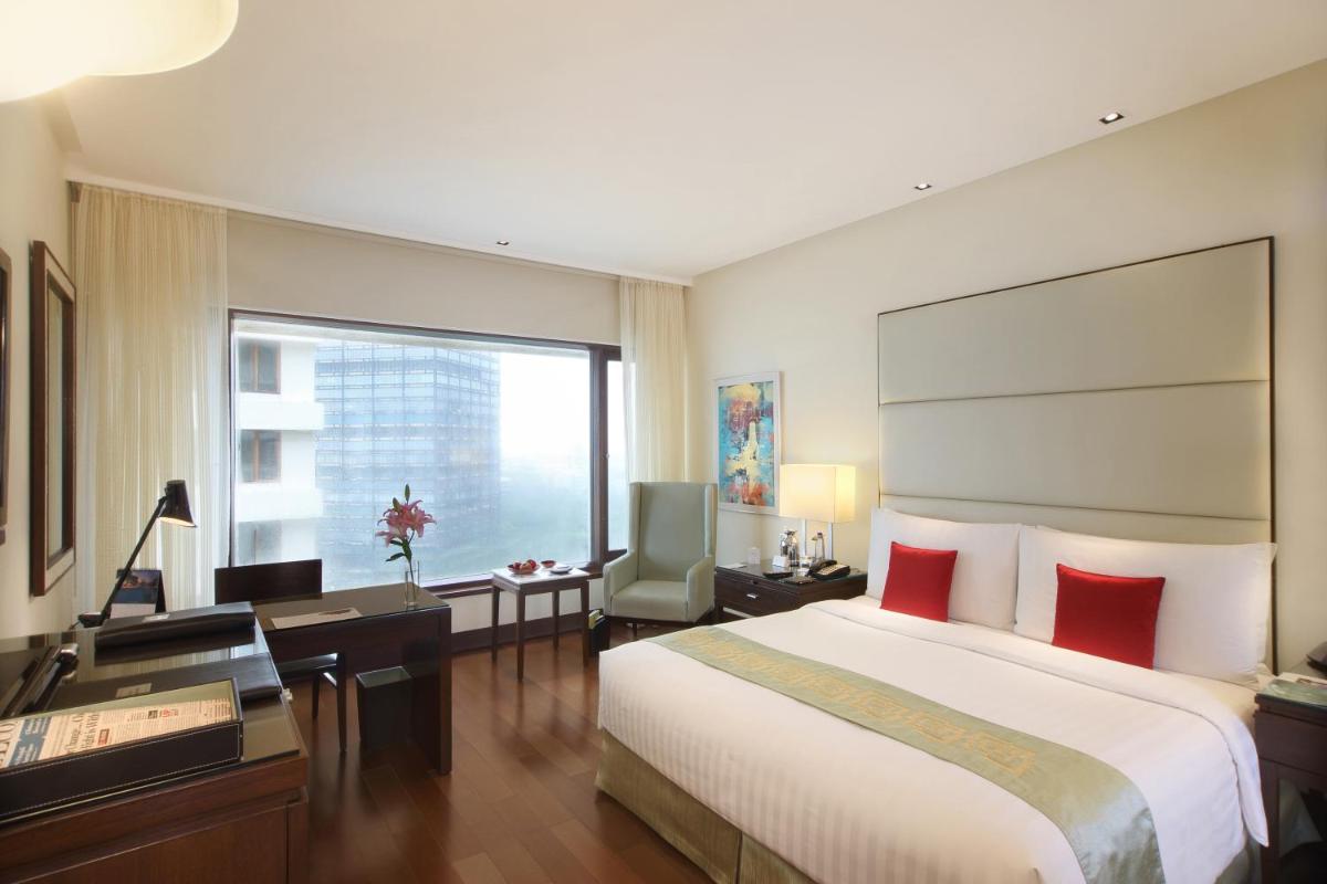 a hotel room with a large bed and a desk at The Oberoi Mumbai in Mumbai