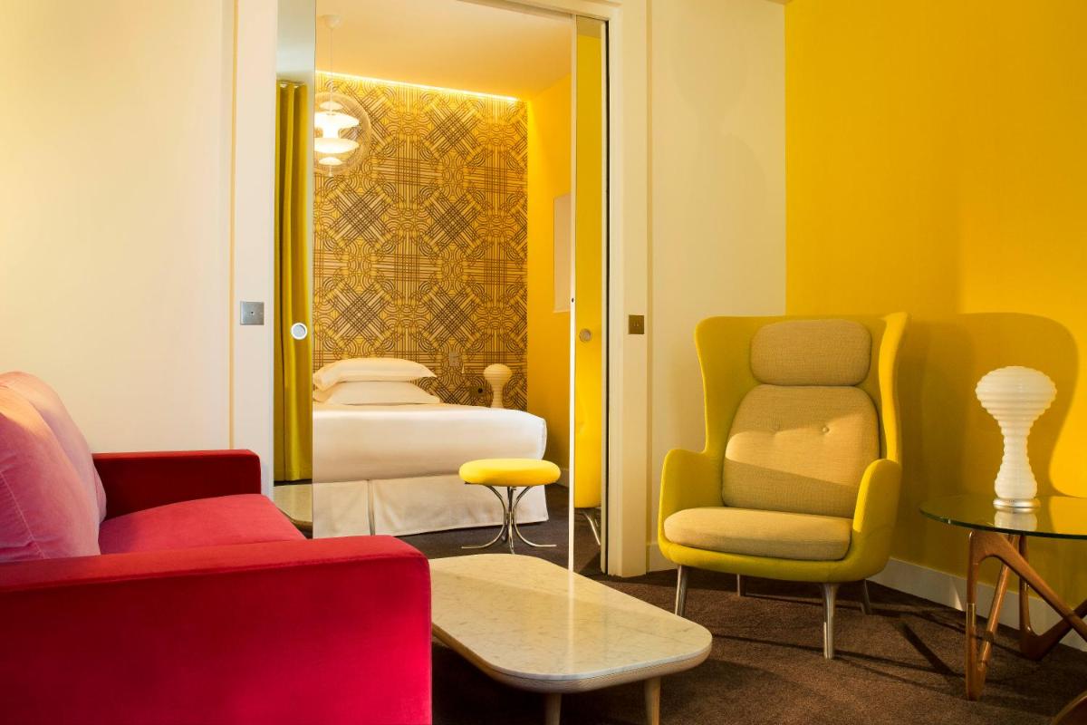 - une chambre avec un canapé, des chaises et un lit dans l'établissement Hotel Dupond-Smith, à Paris