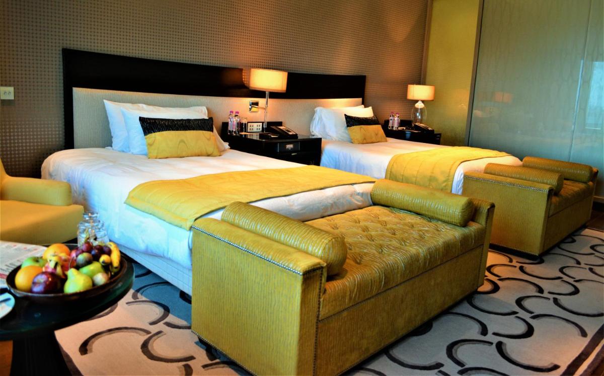 a hotel room with two beds and a couch at Taj Santacruz in Mumbai