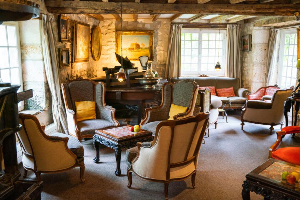 - un salon avec des chaises et un piano dans l'établissement Le Moulin du Roc, à Brantôme