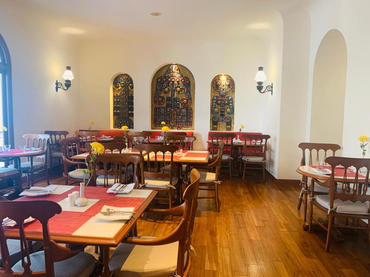 a dining room with tables and chairs and windows at Maidens Hotel New Delhi in New Delhi