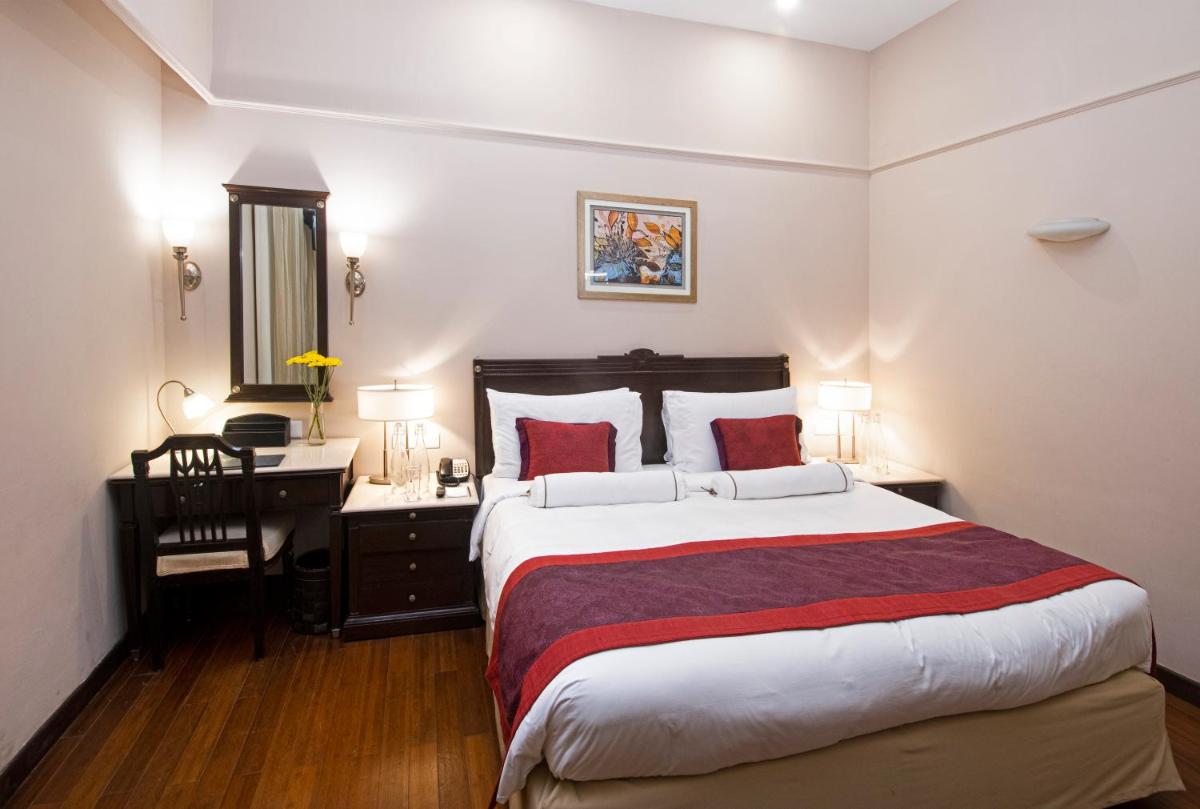 a bedroom with a large bed with a desk and a bed sidx sidx sidx sidx at The Claridges New Delhi in New Delhi a bedroom with a large bed with a desk and a bed sidx sidx sidx sidx at The Claridges New Delhi in New Delhi