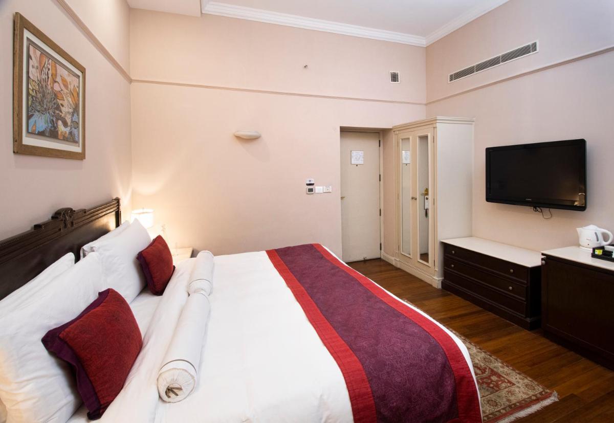 a bedroom with a large bed and a flat screen tv at The Claridges New Delhi in New Delhi a bedroom with a large bed and a flat screen tv at The Claridges New Delhi in New Delhi