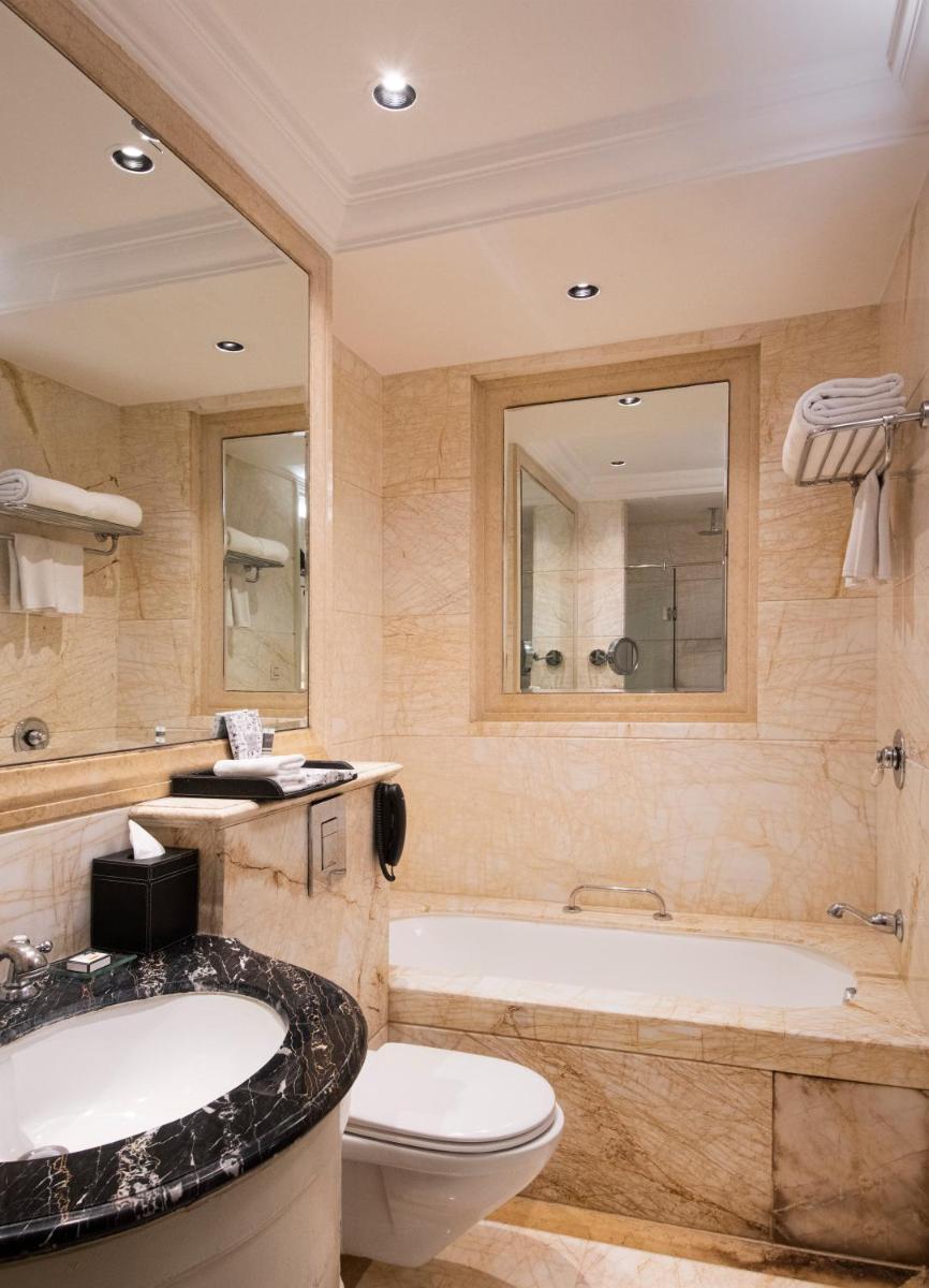 a bathroom with a tub and a toilet and a sink at The Claridges New Delhi in New Delhi a bathroom with a tub and a toilet and a sink at The Claridges New Delhi in New Delhi