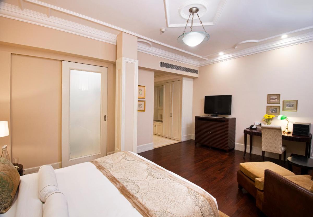 a bedroom with a bed and a tv and a couch at The Claridges New Delhi in New Delhi a bedroom with a bed and a tv and a couch at The Claridges New Delhi in New Delhi