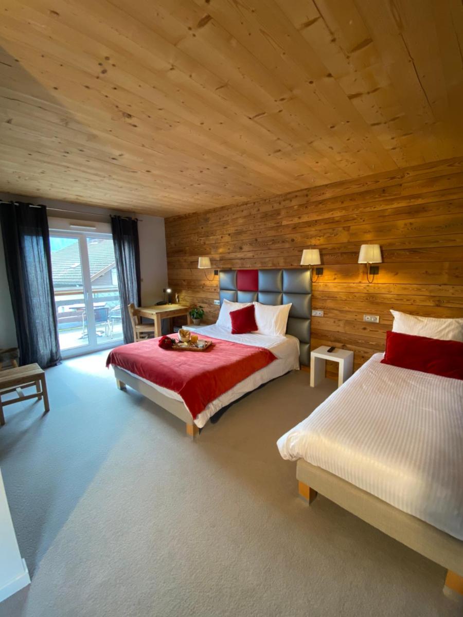 une chambre avec deux lits et un mur en bois dans l'établissement Les Reflets du Lac, à Gérardmer