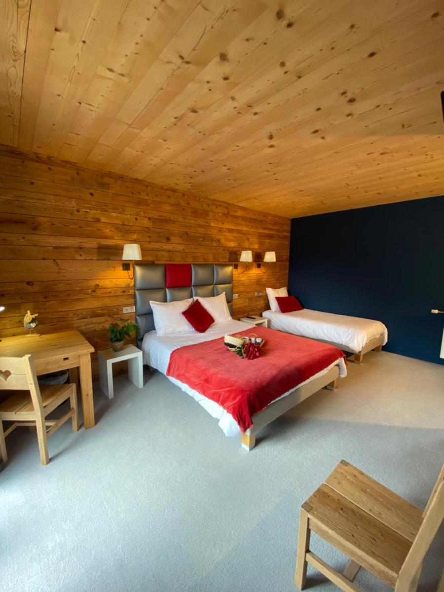 une chambre avec deux lits et un mur en bois dans l'établissement Les Reflets du Lac, à Gérardmer