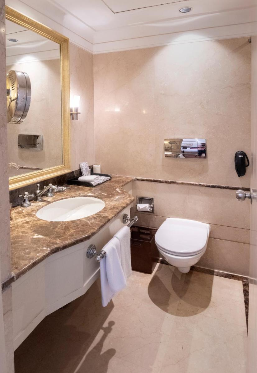 a bathroom with a sink and a toilet and a mirror at The Claridges New Delhi in New Delhi a bathroom with a sink and a toilet and a mirror at The Claridges New Delhi in New Delhi