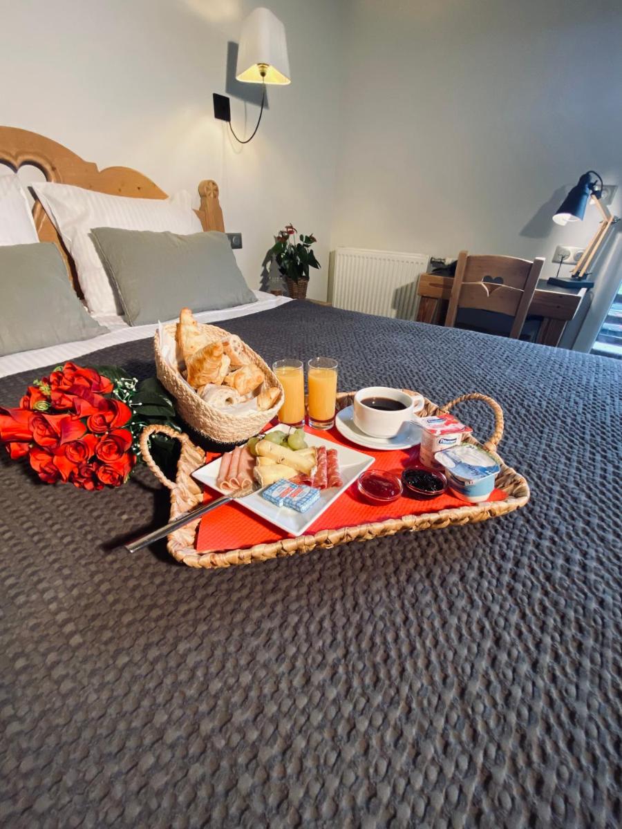un plateau de petit-déjeuner avec de la nourriture et des boissons sur le lit dans l'établissement Les Reflets du Lac, à Gérardmer