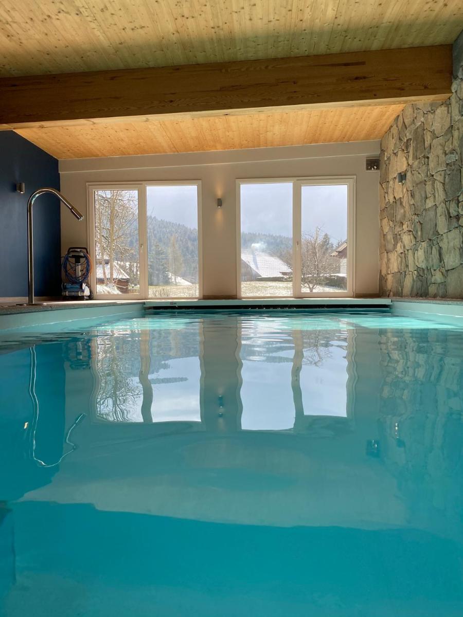 une piscine à l'eau bleue dans une pièce avec des fenêtres dans l'établissement Les Reflets du Lac, à Gérardmer