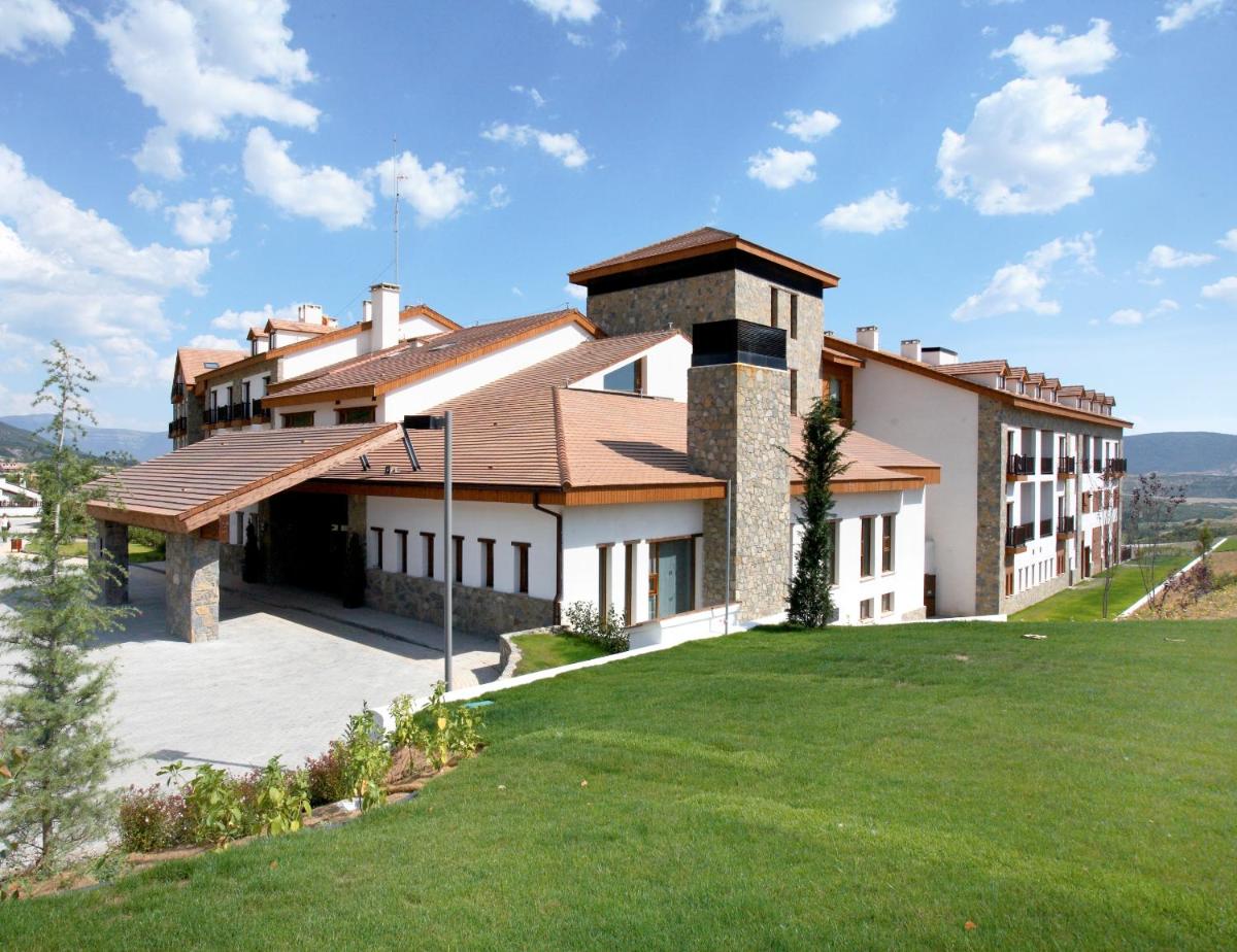 una casa en una colina con césped verde en Hotel & Spa Real Badaguás Jaca, en Badaguás