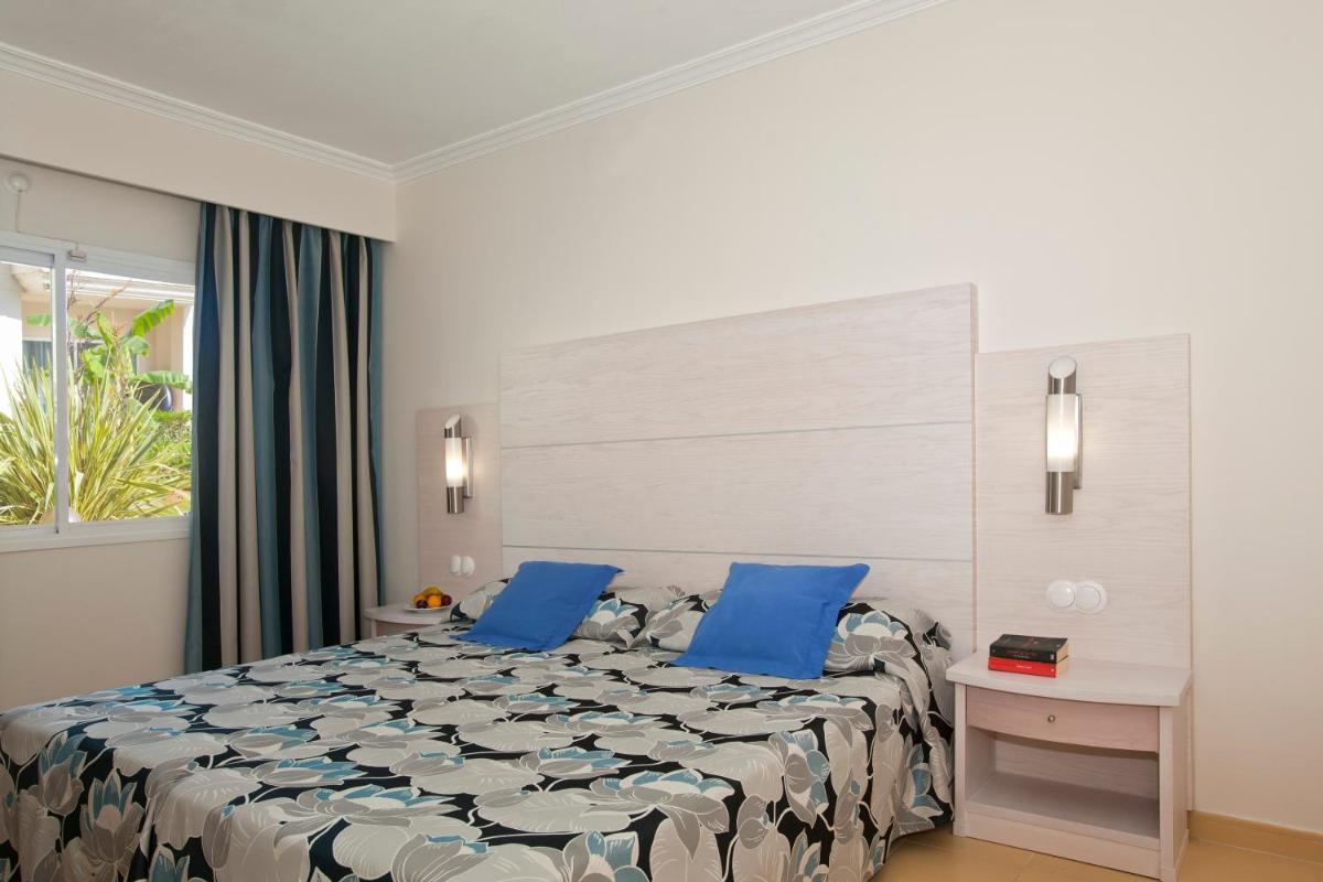 Un dormitorio con una cama grande con almohadas azules. en Aparthotel Isla de Cabrera, en Colonia de Sant Jordi