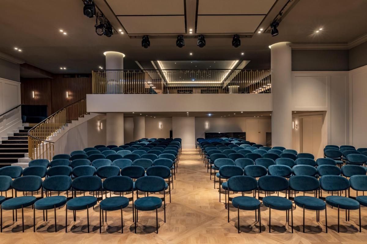 une salle de conférence avec des chaises bleues et une scène dans l'établissement Kimpton - St Honoré Paris by IHG, à Paris 119 autres photos