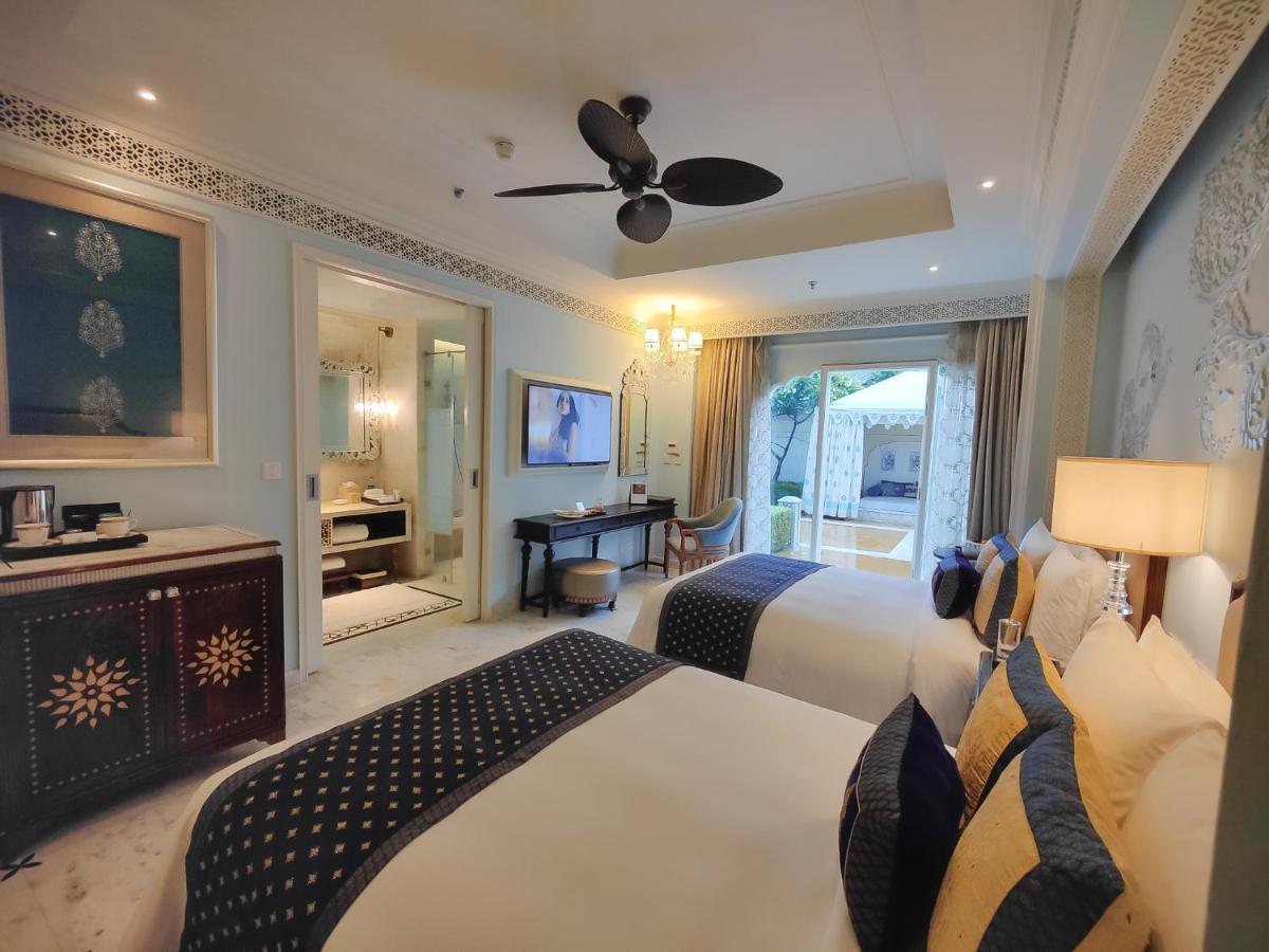 a bedroom with two beds and a ceiling fan at The Leela Palace Jaipur in Jaipur