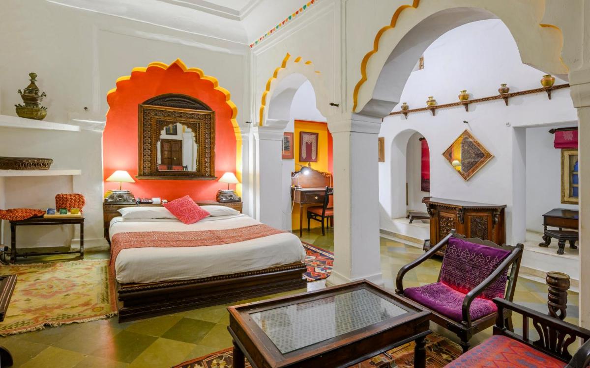 a bedroom with a bed and a desk and a chair at Neemrana Fort-Palace in Neemrana