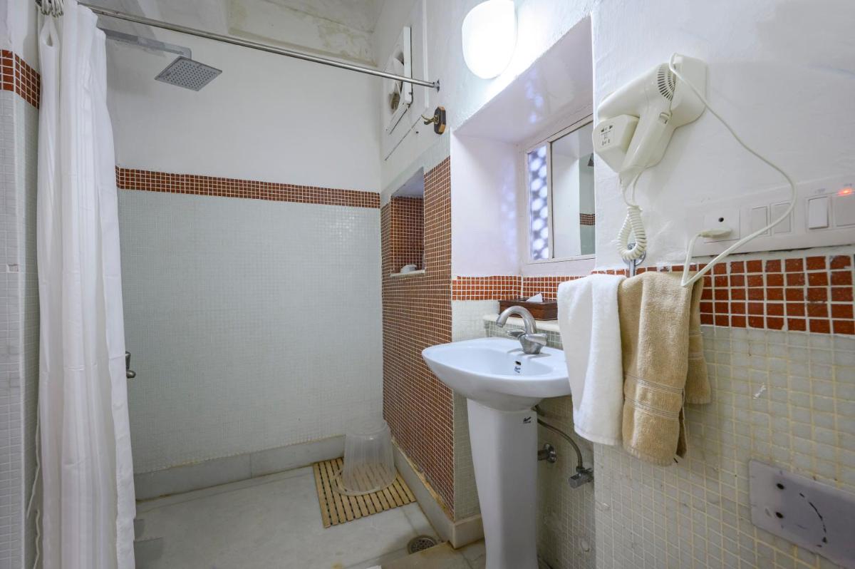 a white bathroom with a sink and a shower at Neemrana Fort-Palace in Neemrana