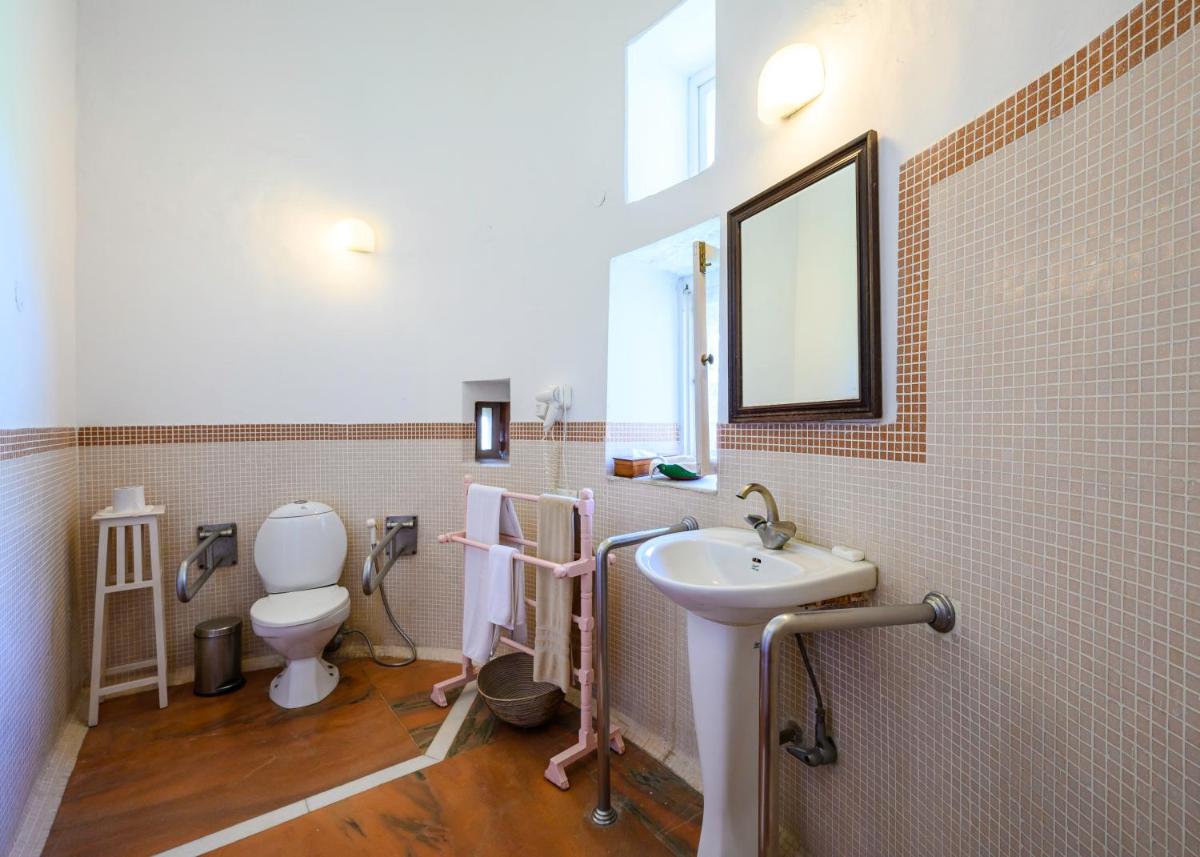 a bathroom with a sink and a toilet and a mirror at Neemrana Fort-Palace in Neemrana