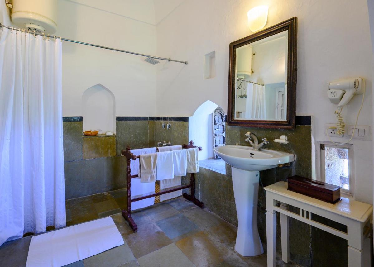 a bathroom with a sink and a shower and a mirror at Neemrana Fort-Palace in Neemrana