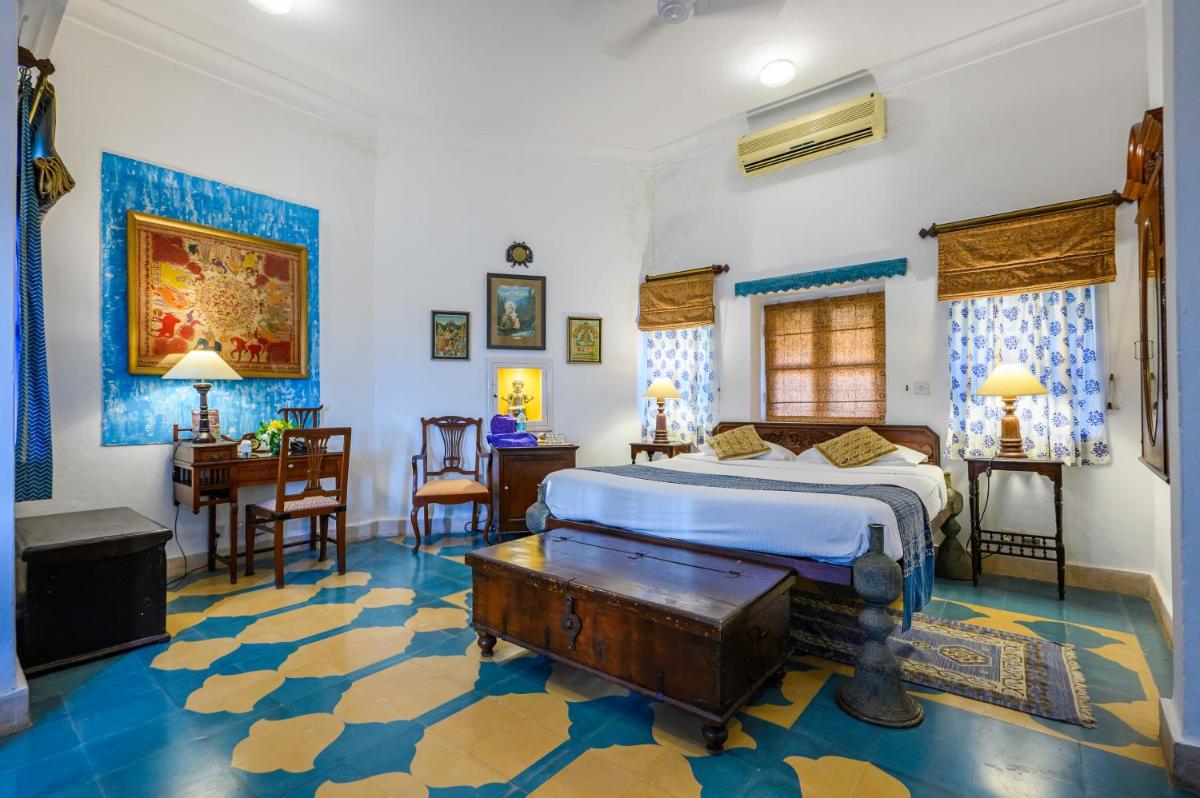a bedroom with a king sized bed and a desk at Neemrana Fort-Palace in Neemrana