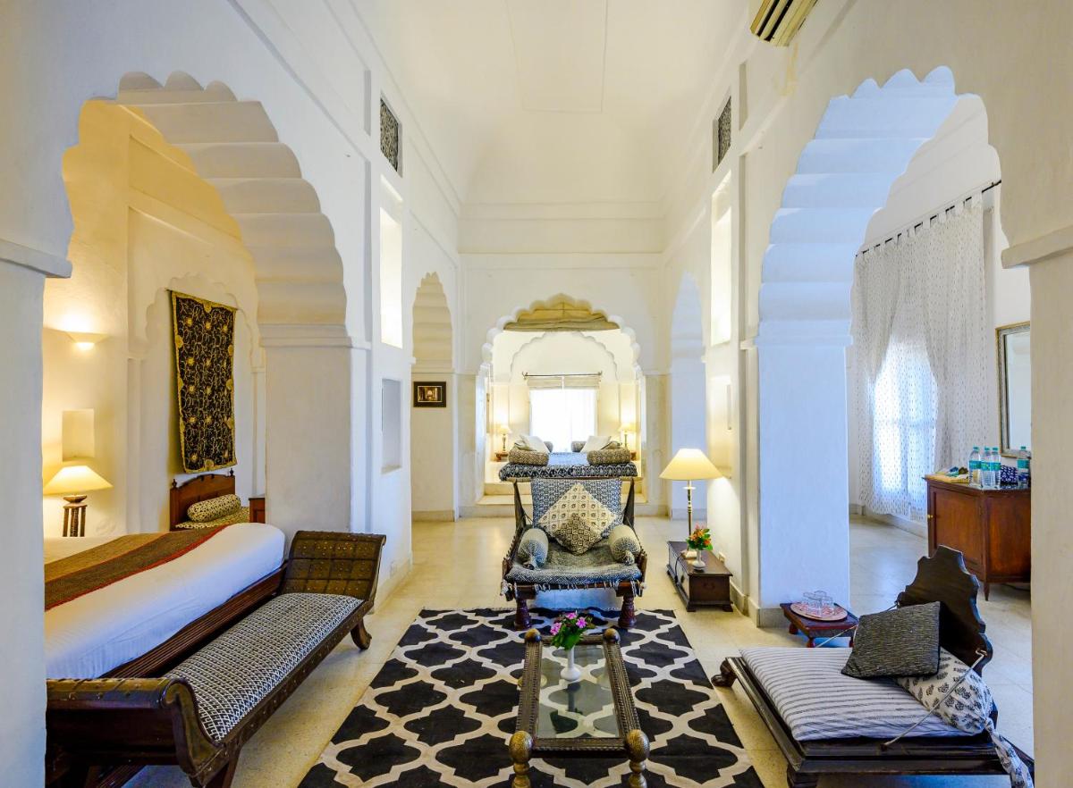a bedroom with a king sized bed and a living room at Neemrana Fort-Palace in Neemrana