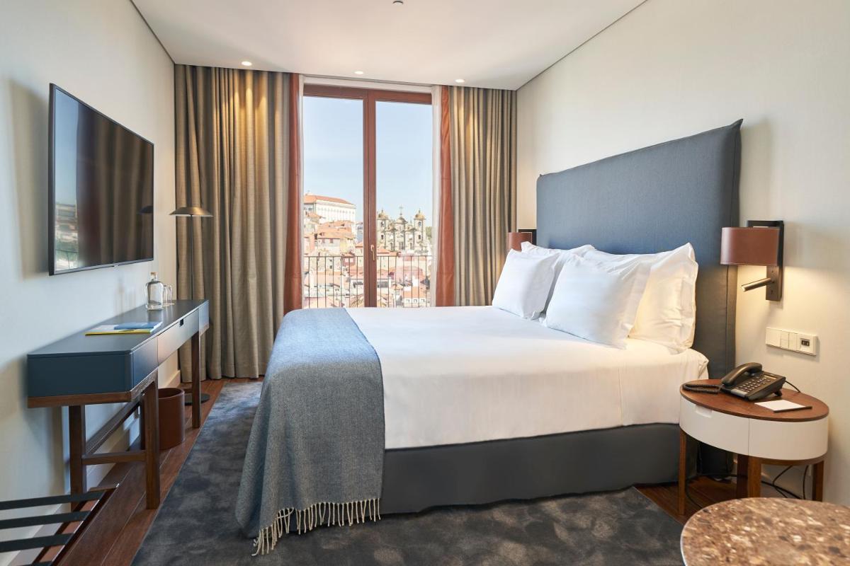 um quarto de hotel com uma cama grande e uma janela em PortoBay Flores no Porto