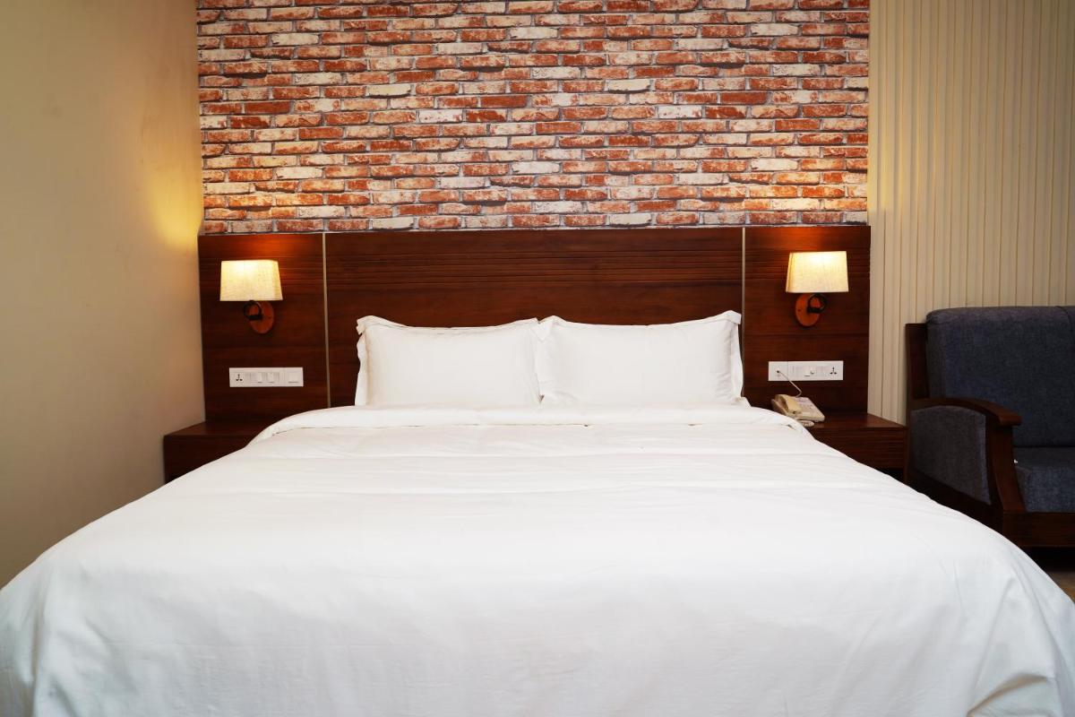 a bedroom with a large white bed with a brick wall at Elephant Passage in Munnar