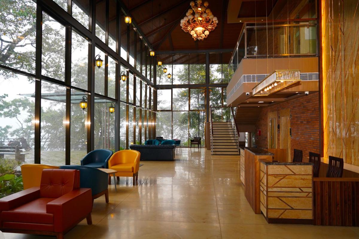 a lobby with yellow and blue chairs and a chandelier at Elephant Passage in Munnar