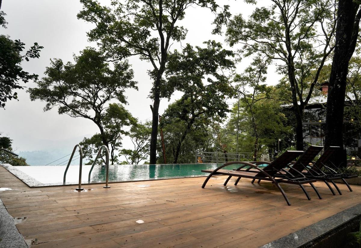 two chairs sitting on a deck next to a swimming pool at Elephant Passage in Munnar